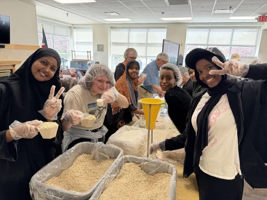 Young volunteers flashing peace signs over trays of oats